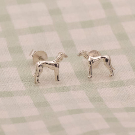 Silver dog-shaped earrings on a checkered fabric background
